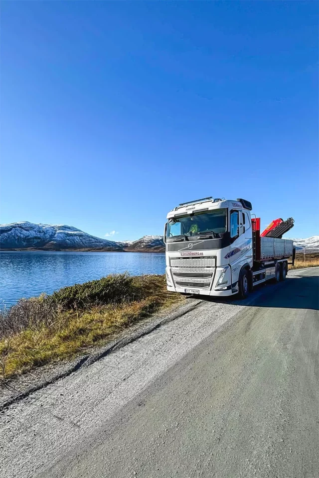 Lastebil parkert ved et vann på fjellet.